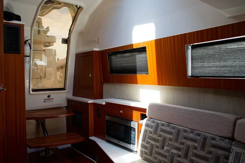 W7 Yacht Photos Pics 2022 Pursuit S 428 Sport interior with wood accents, seating, and kitchenette.