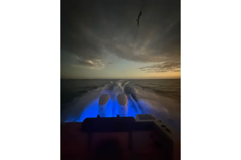  Yacht Photos Pics 2024 Boston Whaler 280 Outrage cruising at dusk with illuminated wake.