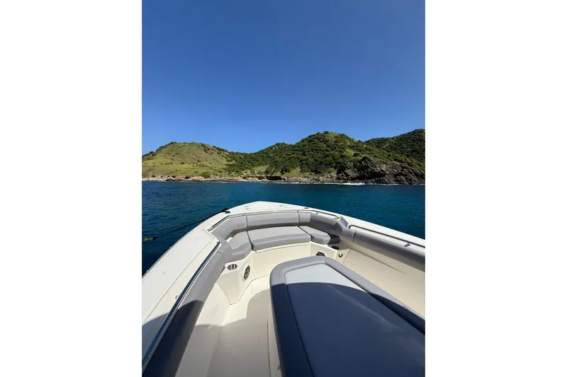  Yacht Photos Pics 2024 Boston Whaler 280 Outrage cruising near lush green island under clear blue sky.