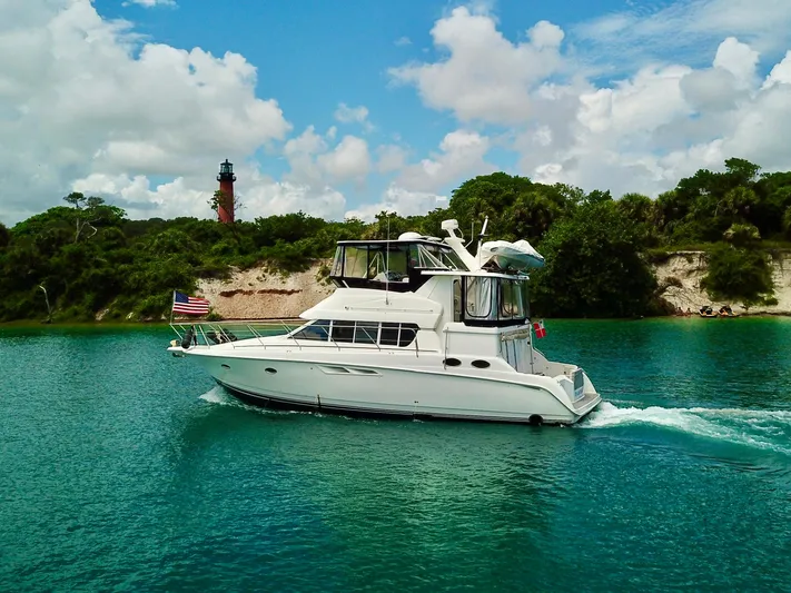  Yacht Photos Pics 2000 Silverton 442 Cockpit Motor Yacht cruising on turquoise water near a lighthouse.