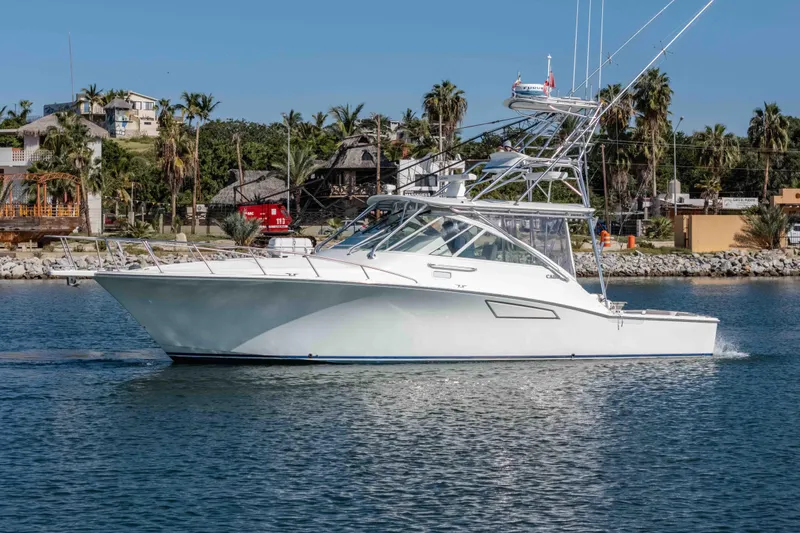  Yacht Photos Pics 2005 Cabo 40 Express yacht cruising on a sunny day near a coastal town.