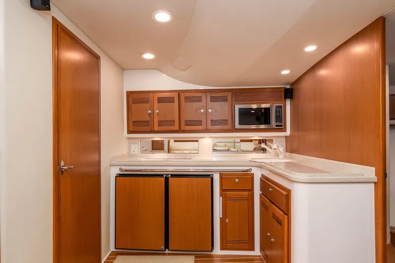  Yacht Photos Pics 2005 Cabo 40 Express yacht kitchen with wood cabinets, microwave, and compact fridge.