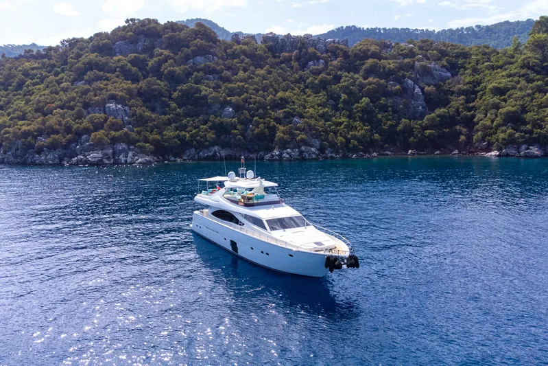 Astarte Yacht Photos Pics 2007 Ferretti Yachts 830 cruising in clear blue waters near a lush, rocky coastline.