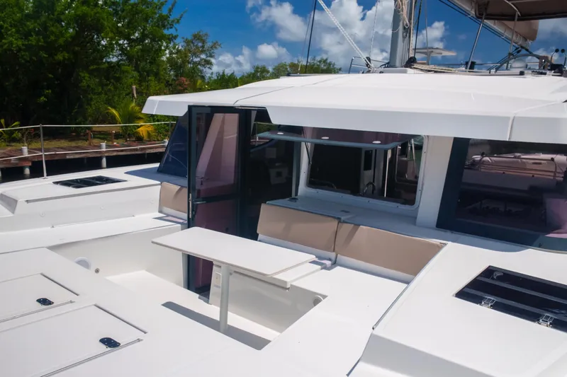 Point Clear Yacht Photos Pics 2023 Bali 4.4 yacht deck with seating and table, surrounded by lush greenery.