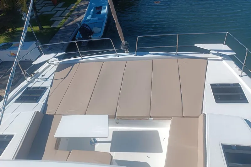 Point Clear Yacht Photos Pics 2023 Bali 4.4 yacht deck with beige sun loungers and table, docked by the water.