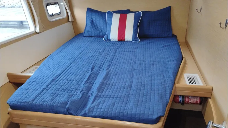 Moon Pearl Yacht Photos Pics Cozy cabin interior of 2008 Lagoon 420 with blue bedding and nautical pillow.