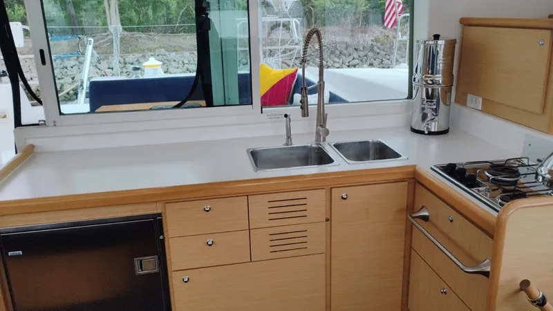 Moon Pearl Yacht Photos Pics Interior of 2008 Lagoon 420 yacht kitchen with sink, stove, and wooden cabinetry.