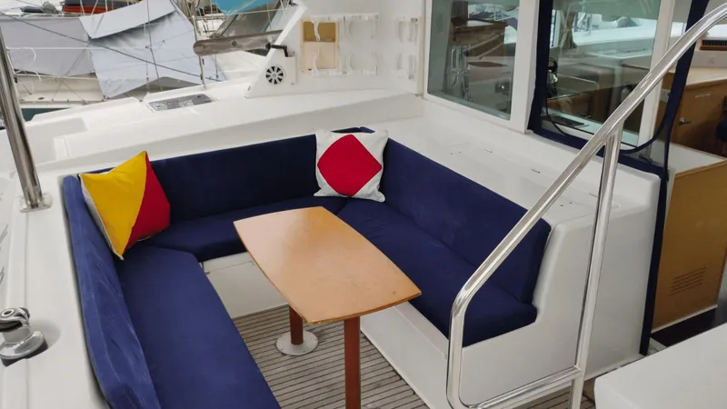 Moon Pearl Yacht Photos Pics 2008 Lagoon 420 yacht interior with blue seating, colorful cushions, and wooden table.