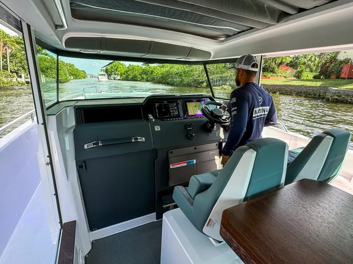  Yacht Photos Pics 2024 Axopar 37XC CROSS CABIN interior with captain navigating through a scenic waterway.