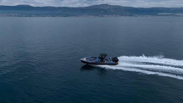  Yacht Photos Pics SuperRib Open 30 boat speeding on calm water, 2025 model, with mountainous coastline in background.