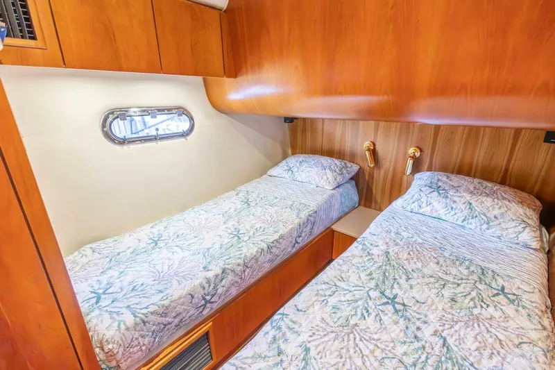  Yacht Photos Pics Twin beds in a 2000 Tiara Yachts 5200 Express cabin with wood paneling and porthole.