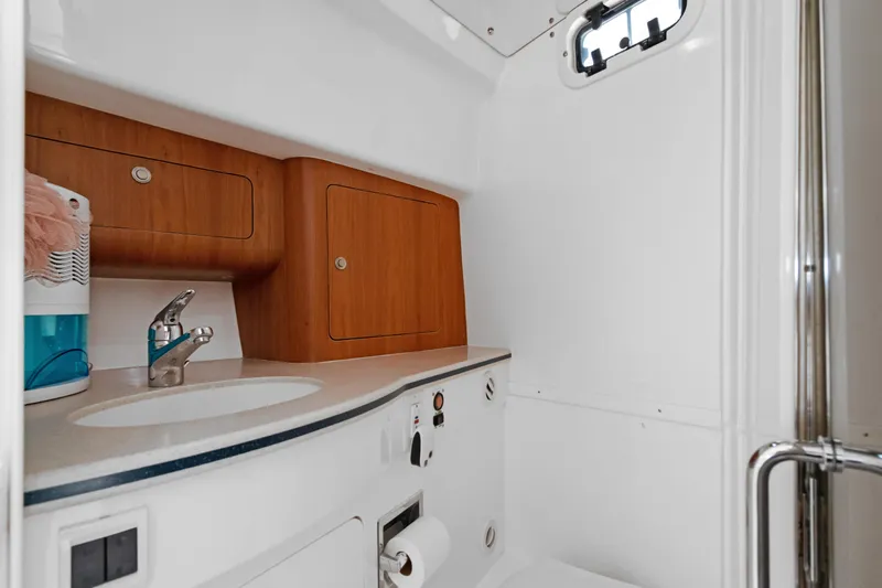  Yacht Photos Pics 2004 Intrepid 377 Walkaround boat bathroom with sink, wooden cabinets, and porthole window.