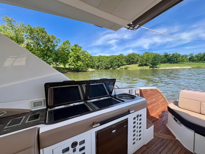  Yacht Photos Pics 2019 Sea Ray SLX 400 boat with outdoor kitchen, scenic lake view, and lush greenery.