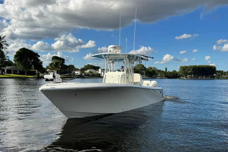  Yacht Photos Pics 2024 SeaVee 290B boat cruising on a serene lake under a partly cloudy sky.