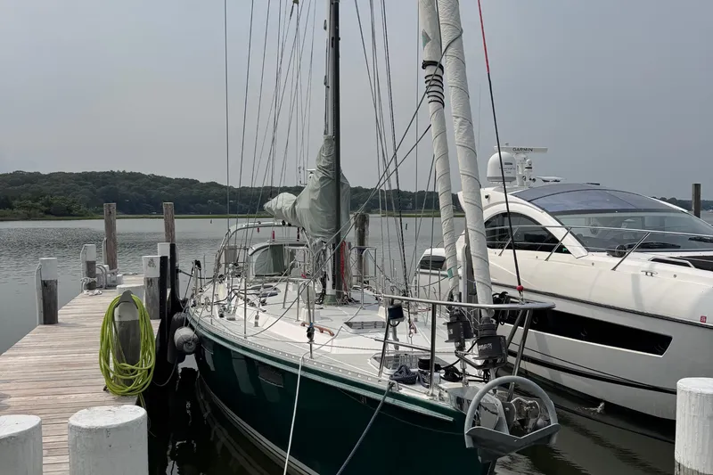 Mara Yacht Photos Pics Sailboat "Able Apogee 50" (1998) docked beside a luxury yacht at a marina.