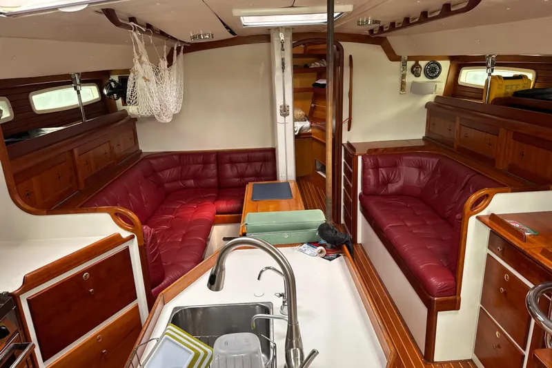Mara Yacht Photos Pics Interior of a 1998 Able Apogee 50 yacht with red leather seating and wooden finishes.