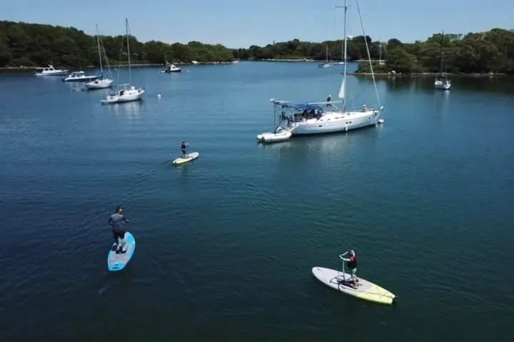  Yacht Photos Pics People paddleboarding near a 2003 Beneteau Oceanis Clipper 423 sailboat on a calm lake.