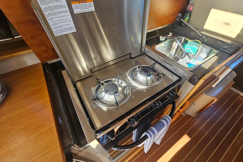 Tuva- B - Lu Yacht Photos Pics Compact kitchen with dual-burner stove in 2015 Cutwater 30 Command Bridge boat.