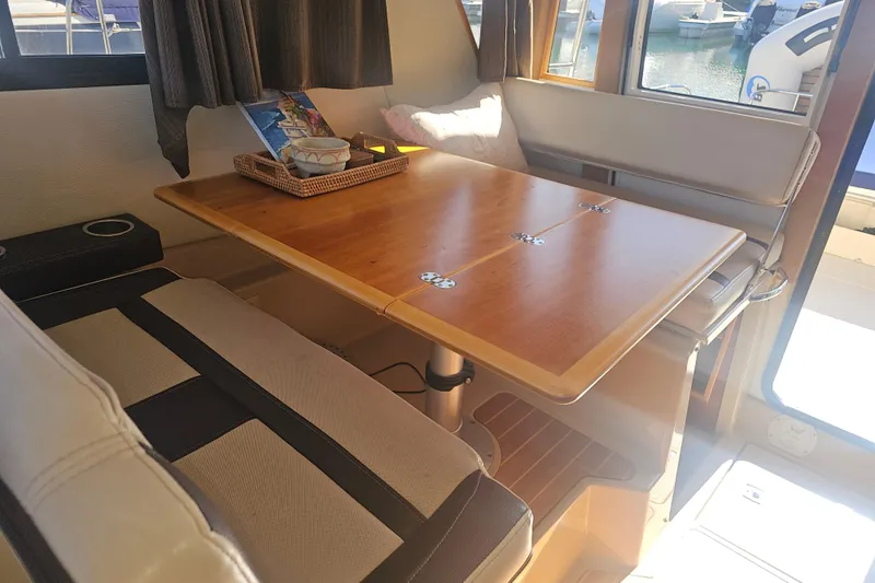 Tuva- B - Lu Yacht Photos Pics Interior of 2015 Cutwater 30 Command Bridge with wooden table and cushioned seating.