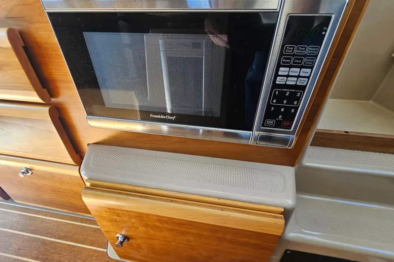 Tuva- B - Lu Yacht Photos Pics Microwave in 2015 Cutwater 30 Command Bridge kitchen with wooden cabinetry.