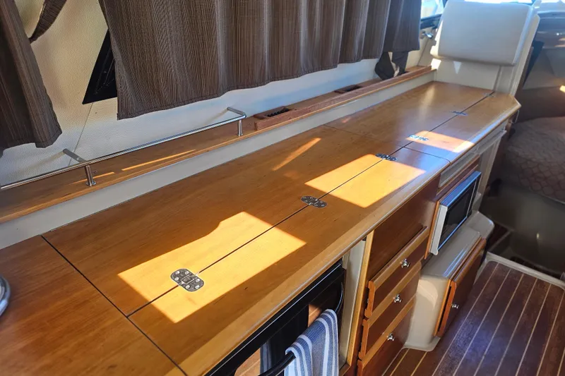 Tuva- B - Lu Yacht Photos Pics Interior of 2015 Cutwater 30 Command Bridge with wooden cabinetry and appliances.