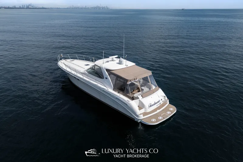  Yacht Photos Pics 1999 Sea Ray Sundancer 540 yacht cruising on open water, city skyline in background.