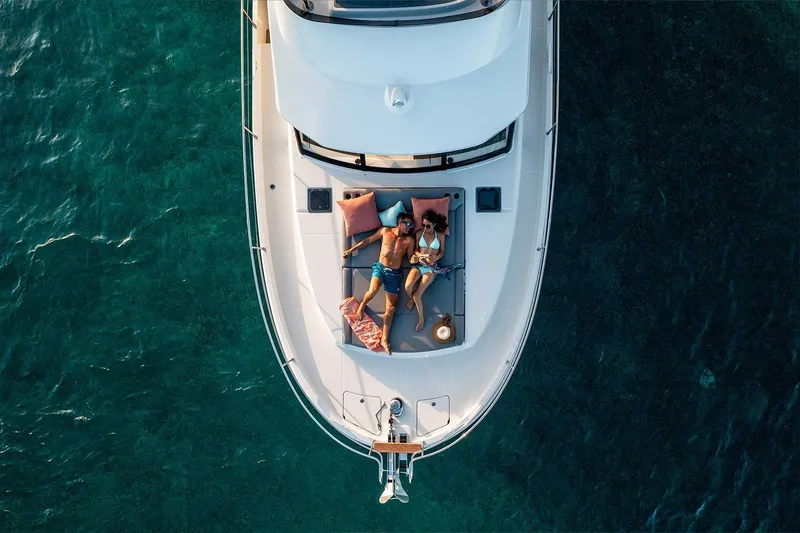  Yacht Photos Pics Couple relaxing on 2026 Beneteau Swift Trawler 48, enjoying the sun on a calm sea.