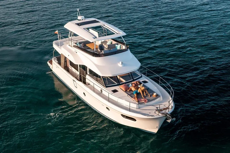  Yacht Photos Pics 2026 Beneteau Swift Trawler 48 cruising on open water, with passengers relaxing on deck.