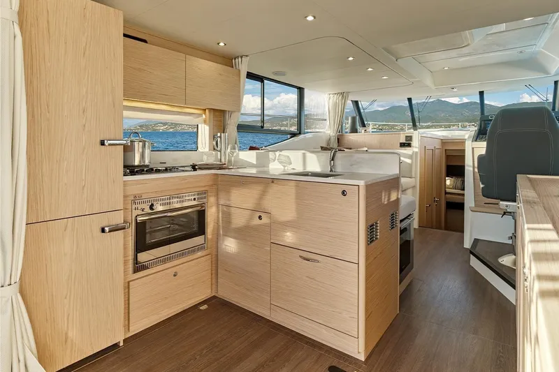  Yacht Photos Pics Modern kitchen interior of 2026 Beneteau Swift Trawler 48 with wood finish and ocean view.