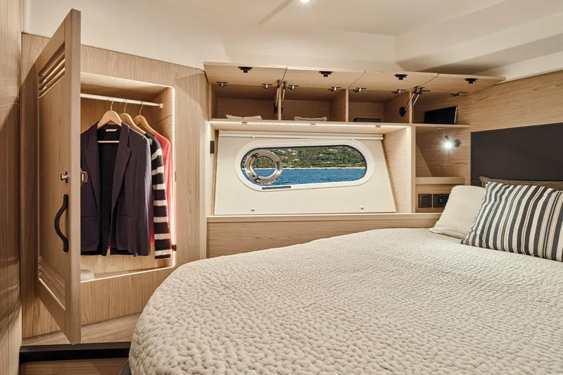  Yacht Photos Pics Luxurious cabin interior of 2026 Beneteau Swift Trawler 48 with wardrobe and porthole view.