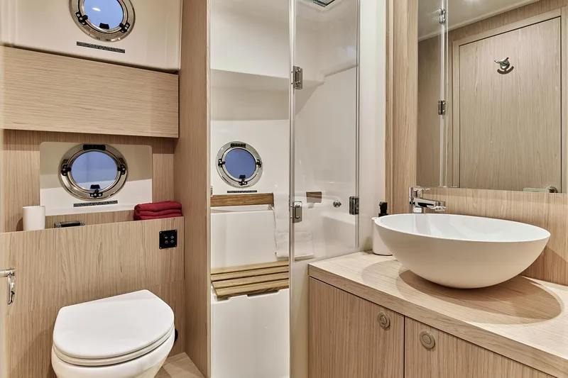  Yacht Photos Pics Luxurious bathroom in 2026 Beneteau Swift Trawler 48 with modern fixtures and porthole windows.