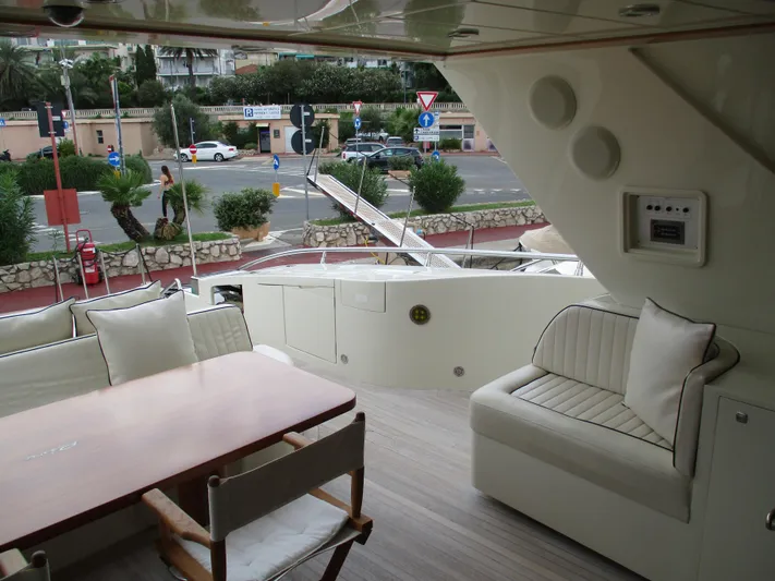 Mr Chic Yacht Photos Pics Luxurious 2001 Riva 84 Cantata yacht interior with seating and table, docked near a road.