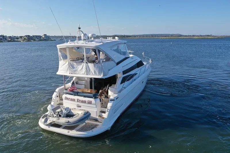 Dream Team Xiii Yacht Photos Pics 2005 Neptunus 56 Flybridge yacht cruising on a serene waterway.