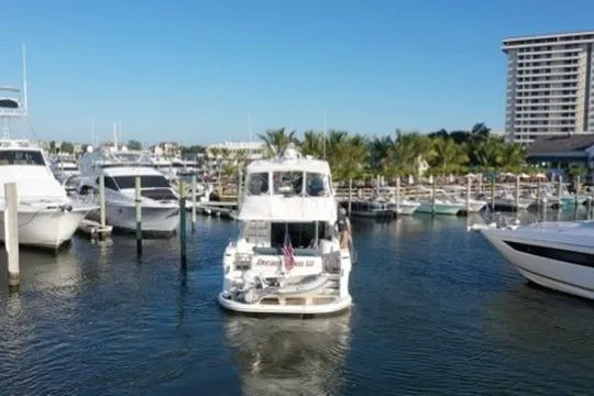 Dream Team Xiii Yacht Photos Pics 2005 Neptunus 56 Flybridge yacht navigating marina with palm trees and high-rise building.