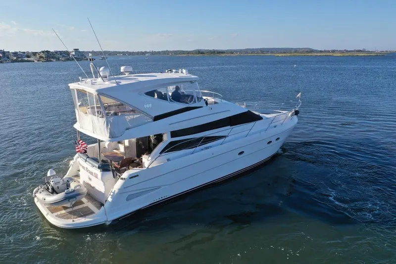 Dream Team Xiii Yacht Photos Pics 2005 Neptunus 56 Flybridge yacht cruising on a serene blue waterway.