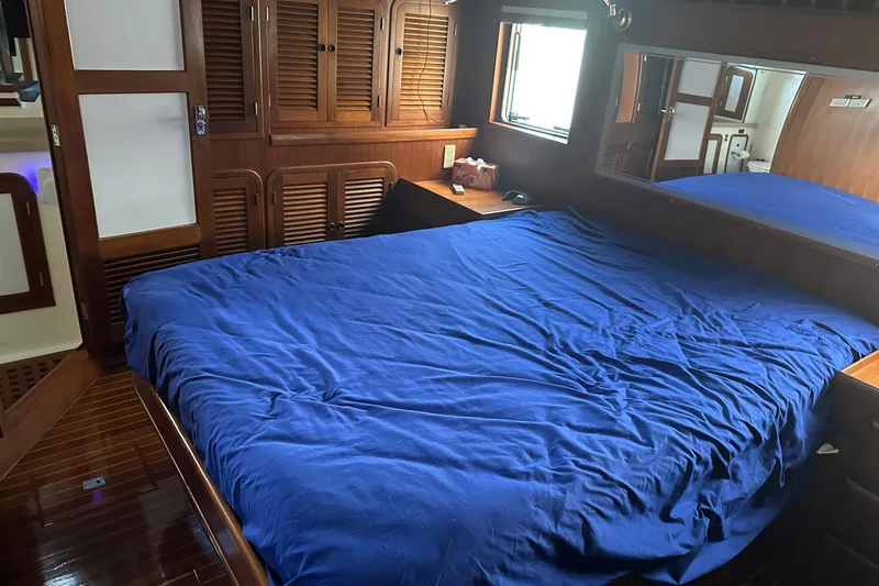 Off Ramp Yacht Photos Pics Luxurious 2002 Novatec Sundeck yacht bedroom with blue bedding and wooden cabinetry.