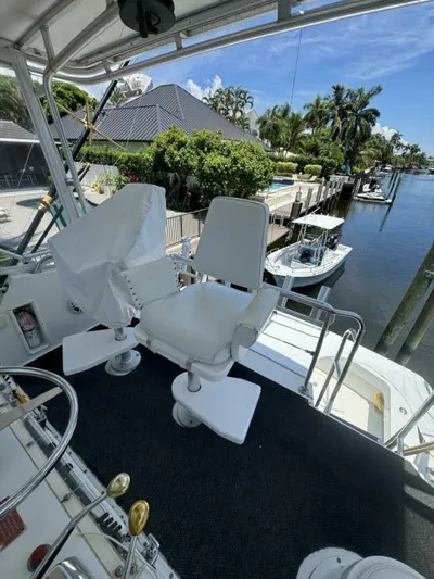 Hook 'em Yacht Photos Pics Captain's chair on 1989 Hatteras 42 Convertible yacht, docked by a scenic waterfront.