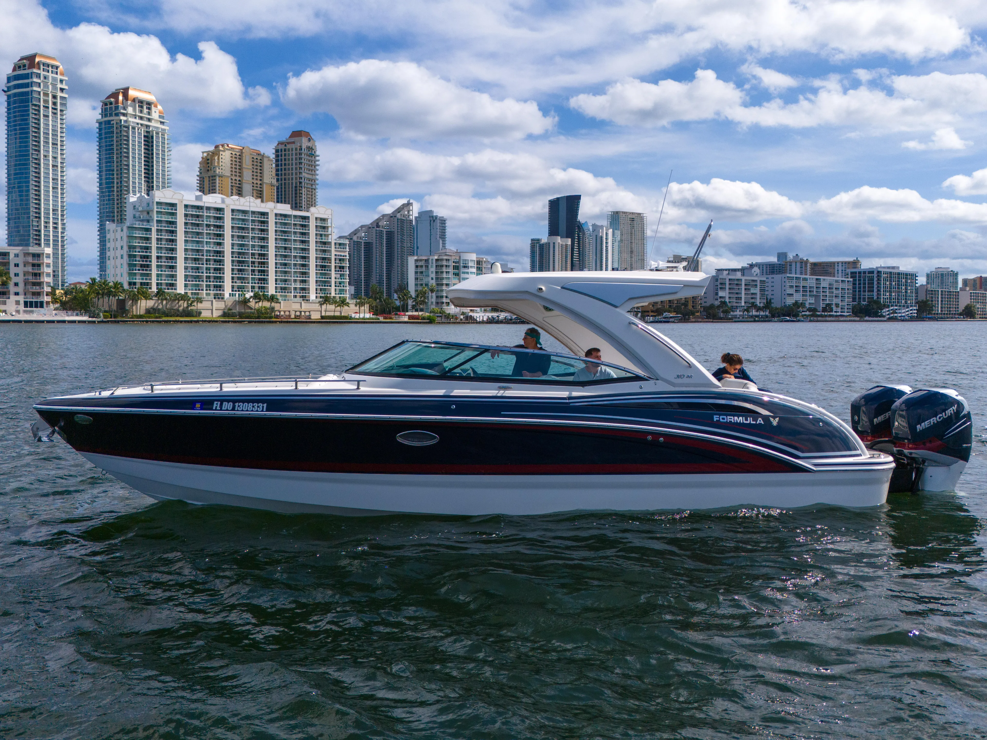 Without A Kaire Yacht Photos Pics 2020 Formula 310 Bowrider cruising on water with city skyline backdrop.
