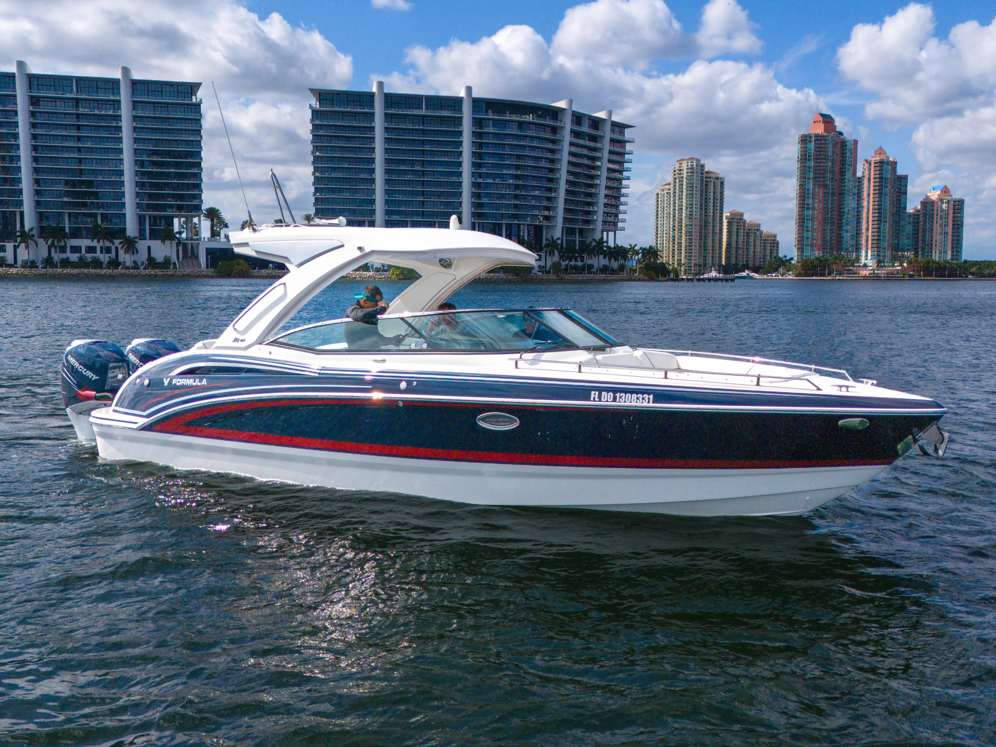 Without A Kaire Yacht Photos Pics 2020 Formula 310 Bowrider boat cruising on water with city skyline background.