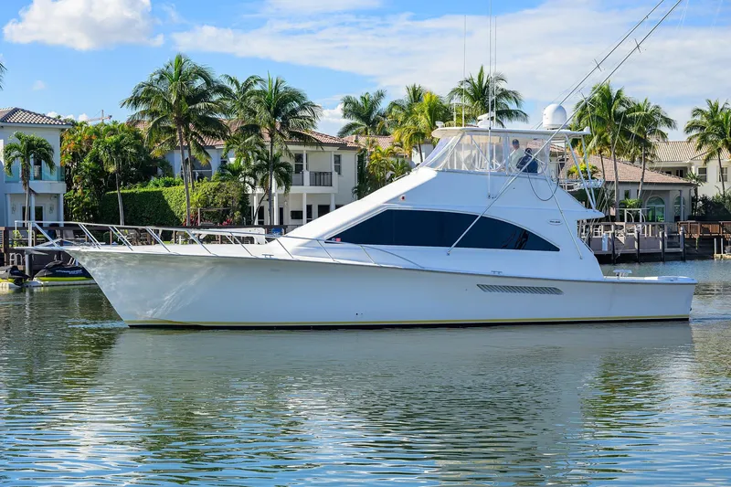 Members Only Yacht Photos Pics 2001 Ocean Yachts Super Sport boat on calm water with palm trees and houses in the background.