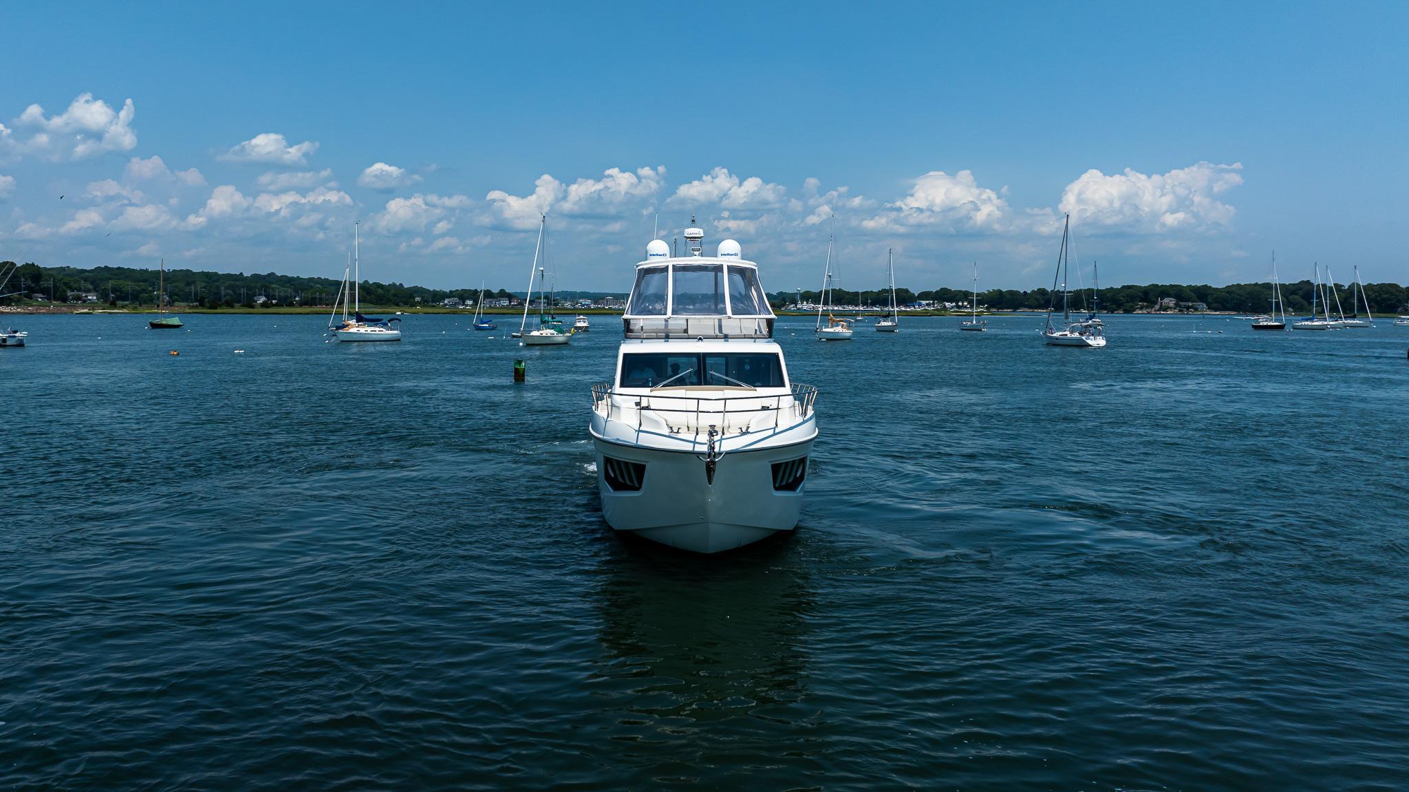 2017 Absolute 50 Fly yacht on a serene lake with sailboats and blue sky.