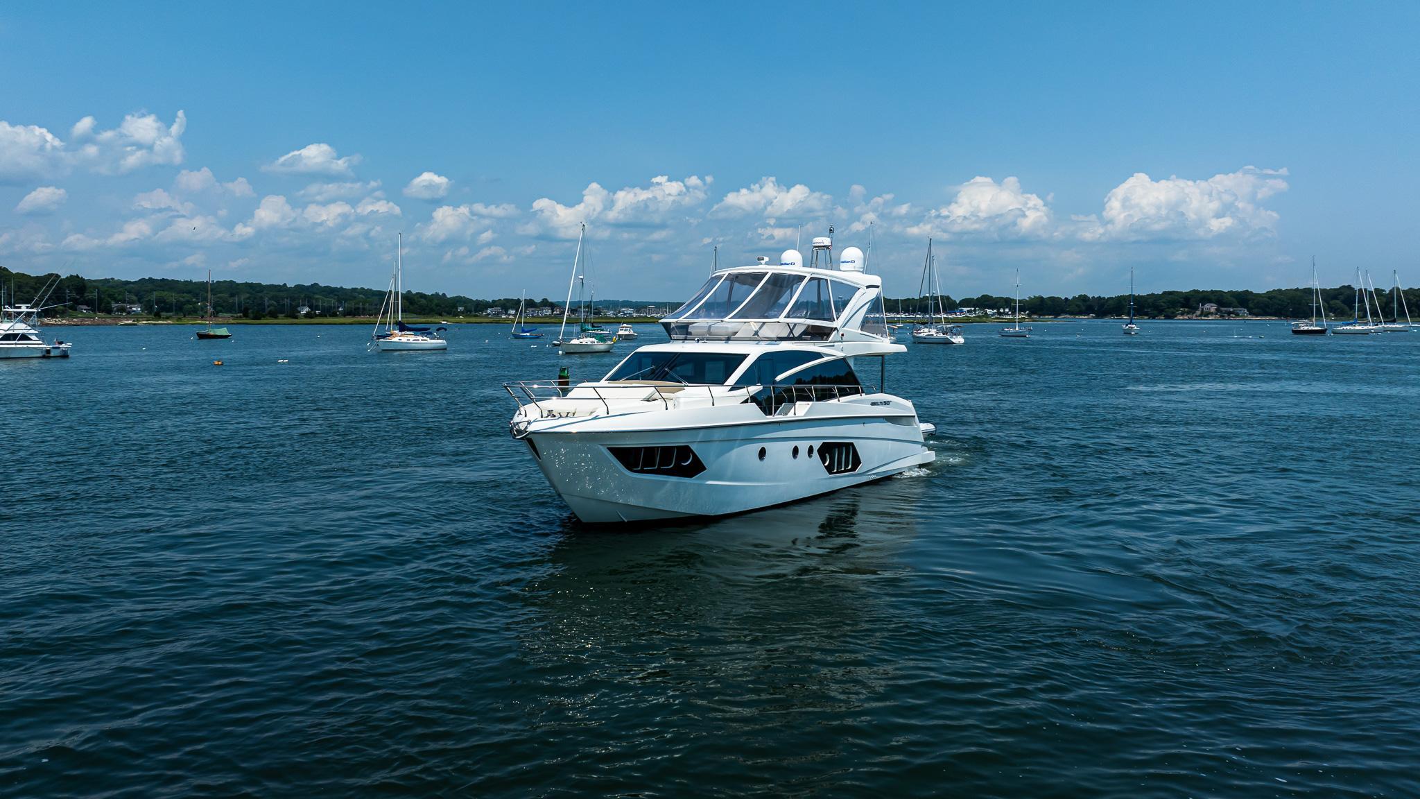 2017 Absolute 50 Fly yacht cruising on a sunny day with sailboats in the background.