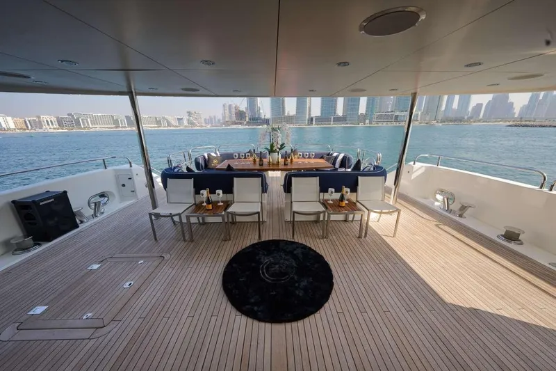  Yacht Photos Pics Luxurious Sunseeker 131 Yacht deck with elegant dining setup, overlooking a stunning waterfront cityscape.