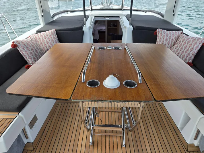 Off-piste Yacht Photos Pics Cockpit of 2019 Beneteau Oceanis 46.1 with wooden table and cushioned seating.