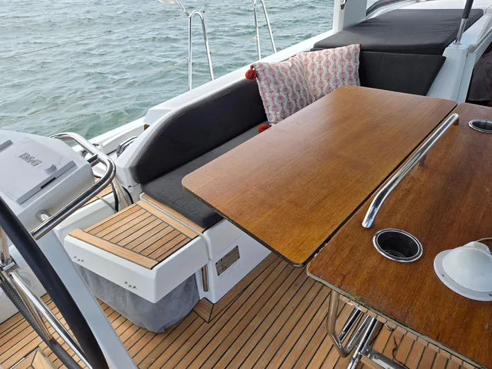 Off-piste Yacht Photos Pics 2019 Beneteau Oceanis 46.1 yacht cockpit with wooden table and cushioned seating.