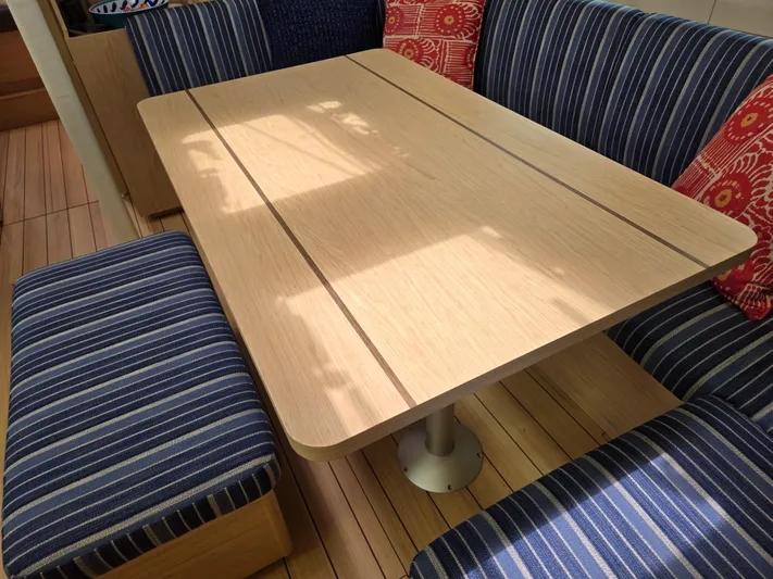 Off-piste Yacht Photos Pics Interior of 2019 Beneteau Oceanis 46.1 yacht with striped seating and wooden table.