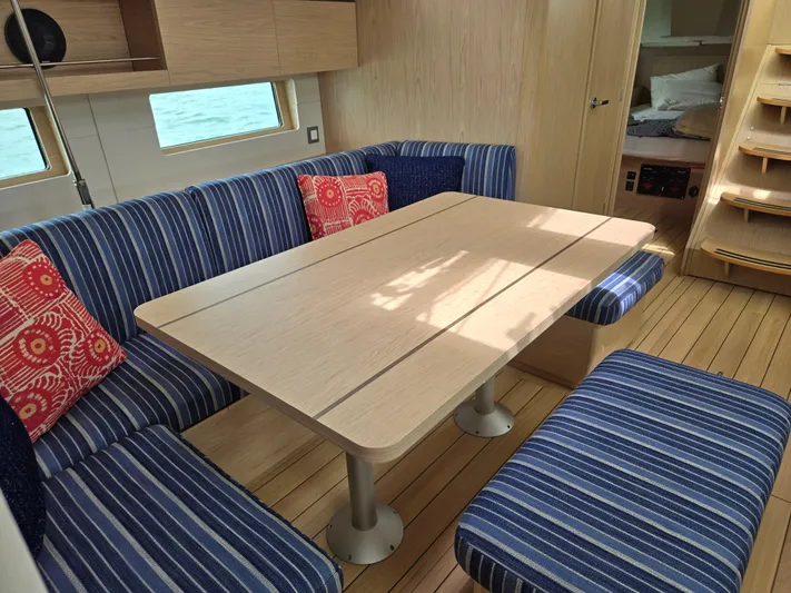 Off-piste Yacht Photos Pics Interior of 2019 Beneteau Oceanis 46.1 yacht with striped seating and wooden table.