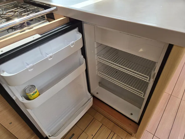 Off-piste Yacht Photos Pics Compact fridge in 2019 Beneteau Oceanis 46.1 yacht kitchen, open with a can inside.