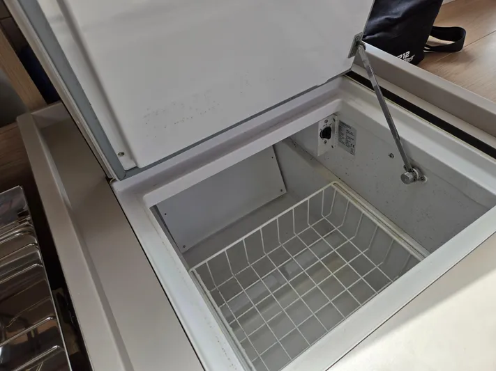 Off-piste Yacht Photos Pics Open freezer compartment on 2019 Beneteau Oceanis 46.1 yacht, showcasing interior storage space.