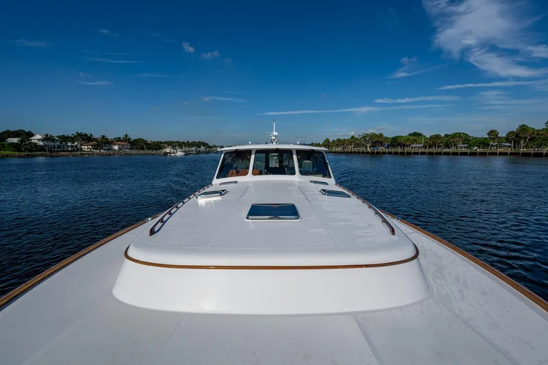 Oldielox 2 Yacht Photos Pics 2019 Hinckley T55 MKII Motor Yacht cruising on a serene waterway under a clear blue sky.